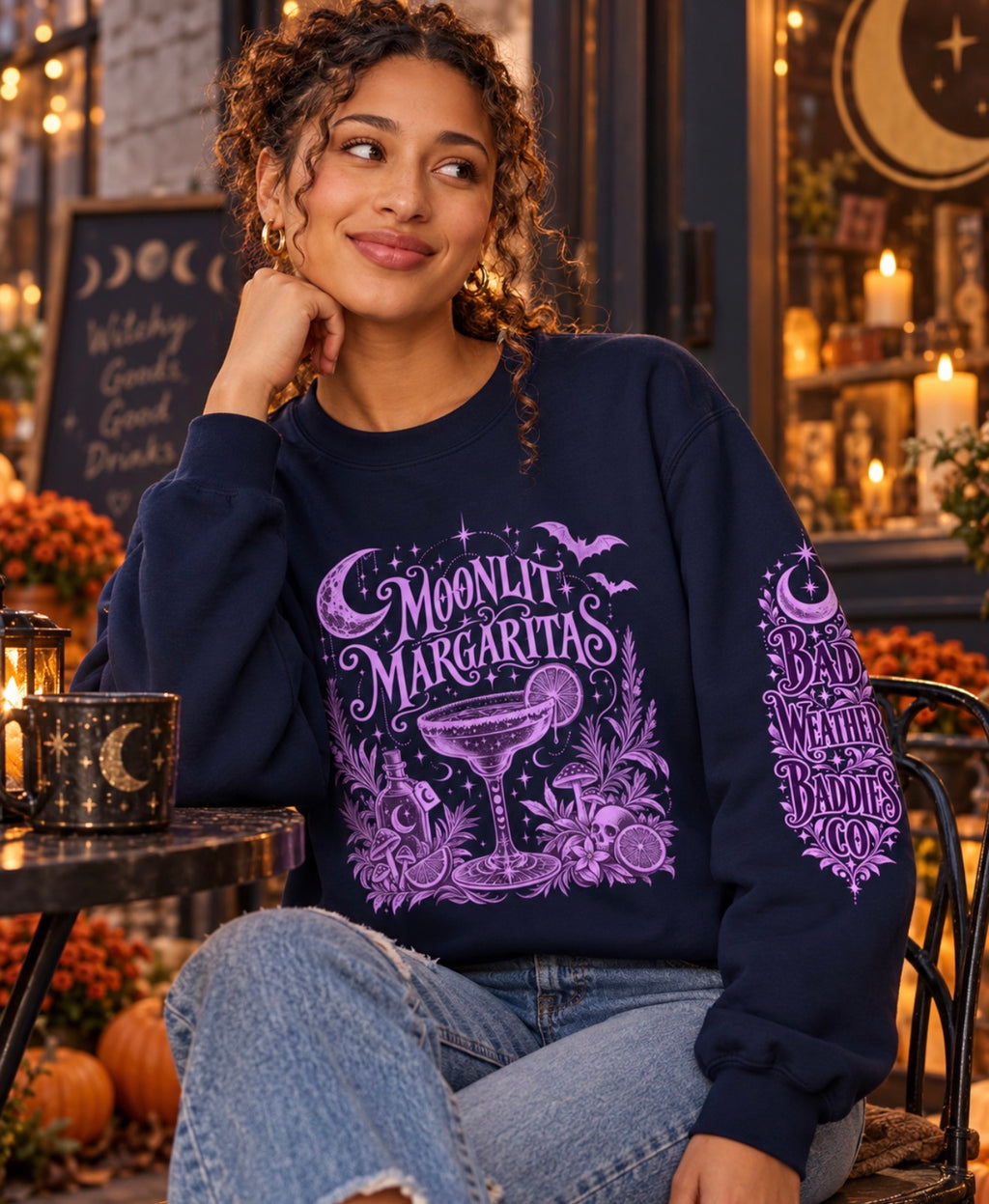 Model wearing Moonlit Margaritas crewneck sweatshirt with purple celestial artwork and Bad Weather Baddies sleeve design